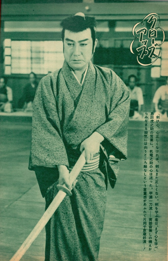 A man in traditional Japanese clothing holds a wooden sword in a dojo setting, appearing serious and focused. The image is rendered in green tones.