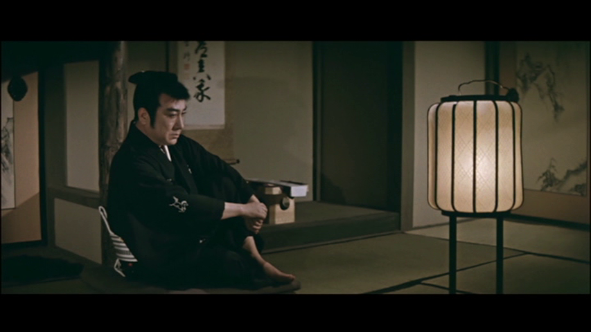 A man in traditional Japanese attire sits on a tatami mat beside a lantern, contemplating in a minimalist room with shoji screens.